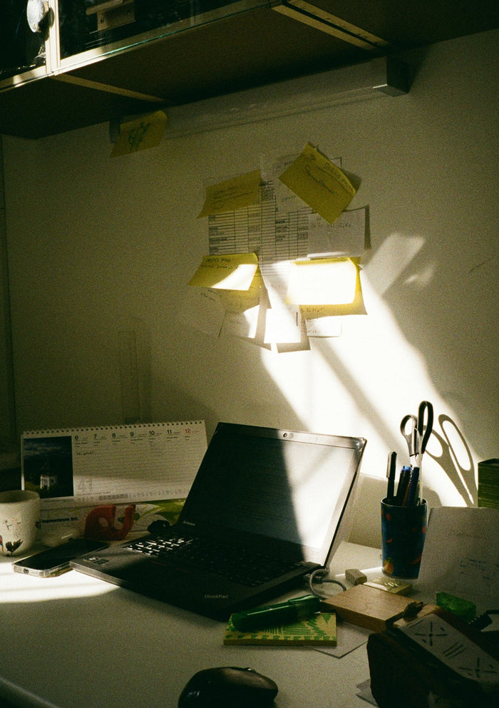 Desk with laptop, sticky notes and sunlight
