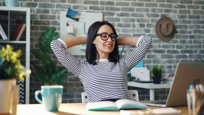 A woman stretching at her desk during a work break
